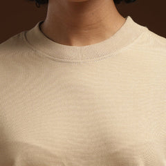 ADEL & VIDA beige oversized t-shirt with a ribbed crew neckline worn by a model with gold hoop earrings.