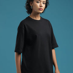 Model wearing an ADEL & VIDA black oversized t-shirt with a soft, breathable fabric against a blue background.