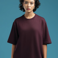 Model wearing an ADEL & VIDA burgundy oversized t-shirt with a soft, minimal design against a blue background.
