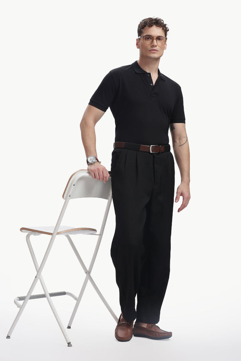 ADEL & VIDA Onyx black regular fit polo t-shirt worn by a model standing next to a white chair