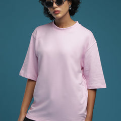 ADEL & VIDA oversized baby pink t-shirt worn by a model with sunglasses against a blue background