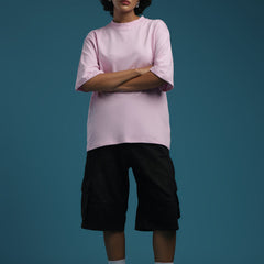 ADEL & VIDA oversized baby pink t-shirt worn by a model with black cargo shorts and sneakers against a blue backdrop