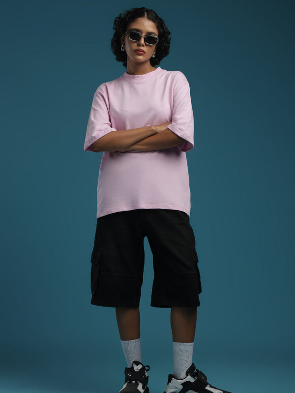ADEL & VIDA oversized baby pink t-shirt worn by a model with black cargo shorts and sneakers against a blue backdrop