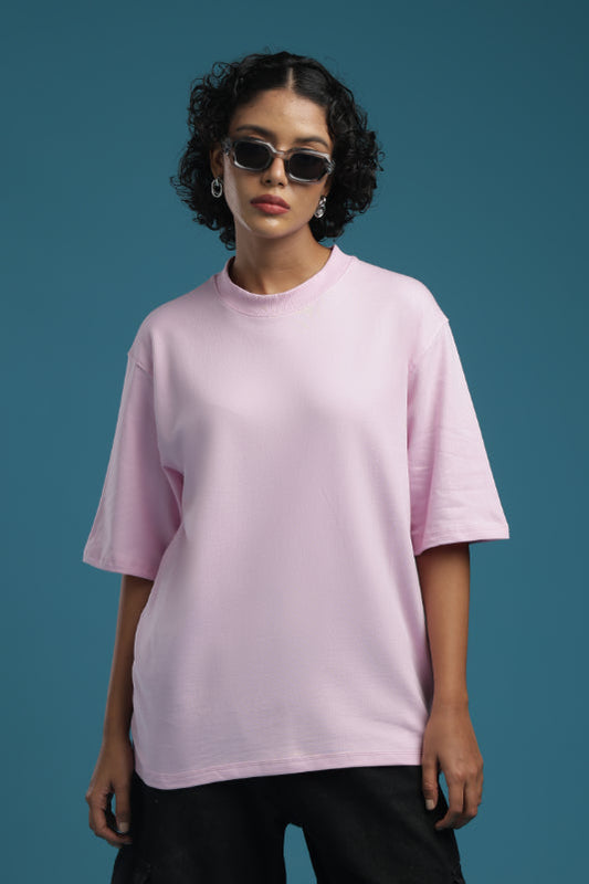 Model wearing an ADEL & VIDA oversized baby pink t-shirt with a crew neck, styled with sunglasses.