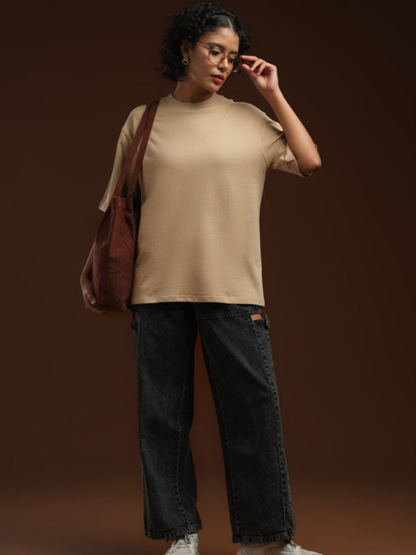 ADEL & VIDA oversized beige t-shirt worn by a model with dark jeans and a brown tote bag against a brown background