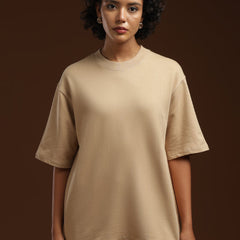 ADEL & VIDA beige oversized t-shirt worn by a model with curly hair against a dark brown background
