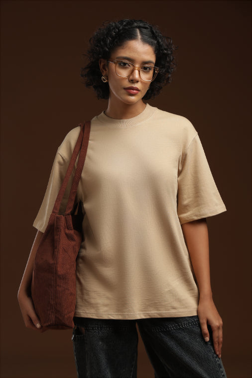 ADEL & VIDA oversized beige t-shirt worn by a woman with glasses and a brown corduroy tote bag