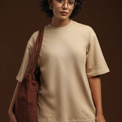 ADEL & VIDA oversized beige t-shirt worn by a woman with glasses and a brown corduroy tote bag