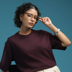 ADEL & VIDA model wearing an oversized burgundy t-shirt with short sleeves against a blue studio background