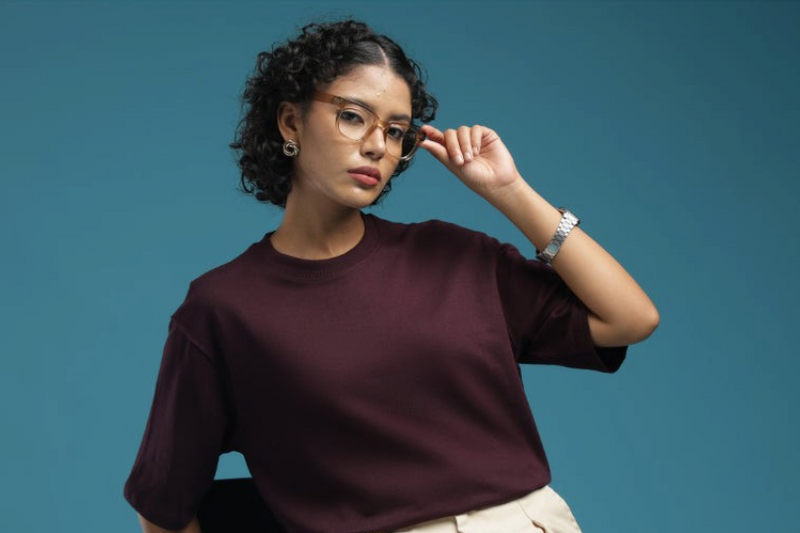 ADEL & VIDA model wearing an oversized burgundy t-shirt with short sleeves against a blue studio background