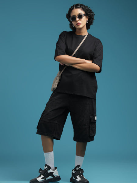 ADEL & VIDA Raven Form oversized black t-shirt worn by a model with black cargo shorts, sunglasses, and sneakers.