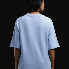 Back view of a woman wearing an ADEL & VIDA oversized sky blue t-shirt with a minimalist solid design.